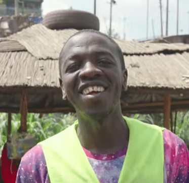 A picture of a smiling young man from Mathare community park, Stanley, at the background of the Mathare Community Park